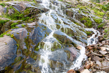 Close-up cascade mountain waterfall in the green mountainside.