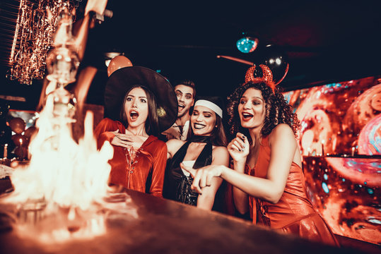 People in Costumes Looking at Flaming Cocktail