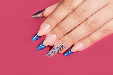 Hand with long artificial blue french manicured nails, pink background