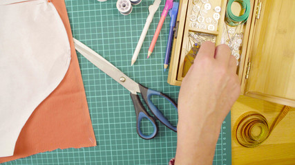 Middle-age woman hands pinning a paper pattern to the fabric with pins. Handmade clothes.