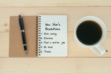 New Year's Resolutions list on notepad with pen and cup of coffee