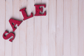 Word sale in red letters on a wooden background, space for inscriptions. Photo format horizontal