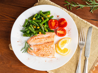 Fish salmon steamed with vegetables. Healthy diet food, dark wooden backdrop, top view, close-up
