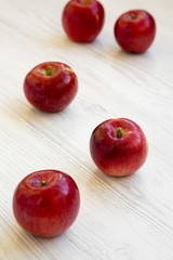 Fresh raw red apples on white wooden background, low angle view. Close-up. Selective focus.