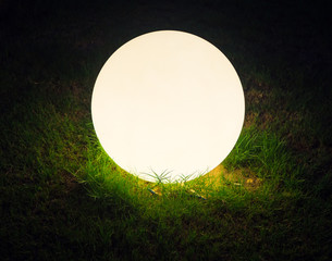 Bright glowing ball in the grass with black background, close up