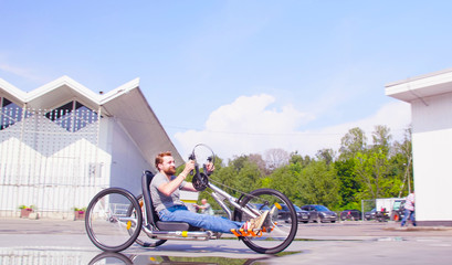 Happy young disable man is riding hand bike in the park and smiling.
