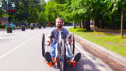 Face view of happy young disable man riding hand bike in the park. He smiling.