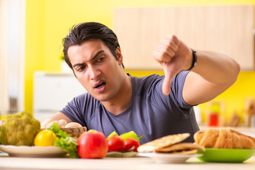 Man having hard choice between healthy and unhealthy food