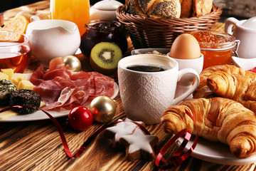 breakfast on table with bread buns, croissants, coffe and juice on christmas day. xmas holiday morning.