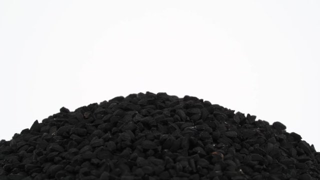 Macro shooting of upper part of black caraway pile. Rotating on the turntable. Isolated on the white background. Close up.