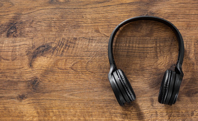 wireless Black headphones on wooden table background with copy space. top view