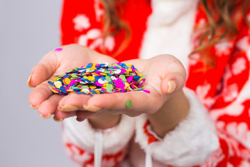 Celebrating, christmas concept - colourful confetti decorations and glitter in woman's hands close up