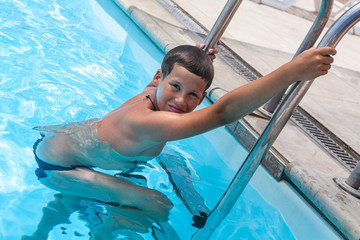 Caucasian boy leaves pool after swimming. Safety concept in pool