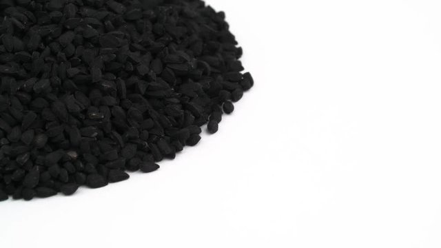 Half frame. Pile of black cumin. Vertically rotating. Isolated on the white background. Close up. Macro.