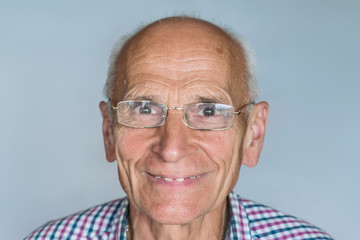 An elderly man with glasses smiling broadly