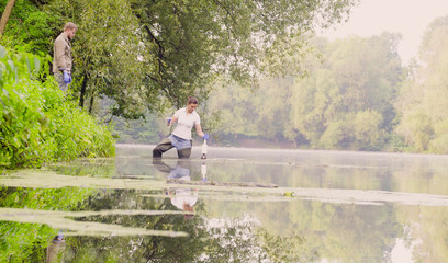 Panorama. Two ecologist getting samples of water in city park. Scientific fieldwork. Early morning