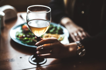 Female hand with glass of wine and food in the background