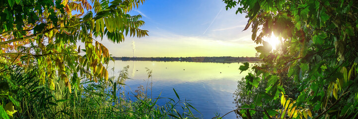 Naklejka premium Grüne Blätter vor blauem See, Wunderschöner Natur Hintergrund