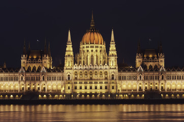 Fototapeta na wymiar Night view of the illuminated building of the hungarian parliament in Budapest. A beautiful reflection of the parliament building on the Danube River. Winter city night landscape.