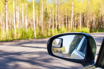 Obraz premium View in the side mirror of the road, forest background