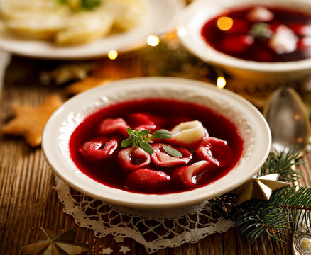 Christmas beetroot soup, borscht with small dumplings with mushroom filling in a ceramic bowl on a wooden table.  Traditional Christmas eve dish in Poland. 