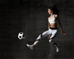 Soccer woman player jumps and hit the ball strike in the middle on concrete loft wall 