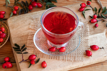 A cup of rose hip tea with fresh rose hips on a table