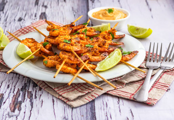 Grilled Shrimp /Prawn on the Skewers Served on a White Plate with Sauce and Lemon