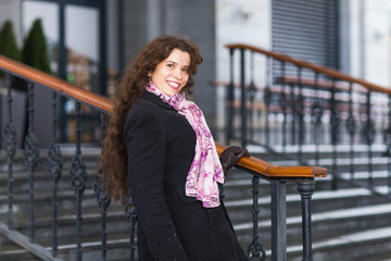 People, fashion and winter concept - young woman posing in coat with on stairs background