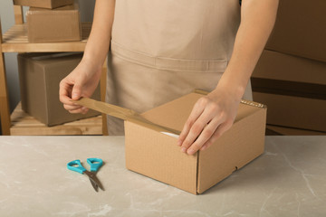 Woman packing box at table, closeup. Space for design