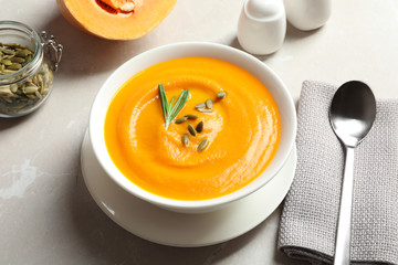 Bowl with tasty pumpkin soup served on gray table