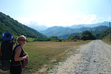 Fototapeta na wymiar A woman with backpack hiking into Carpathian Mountains, view nature of Transylvania, Romania