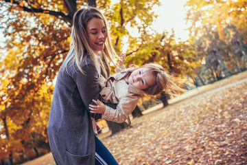 Fototapeta na wymiar Mother and daughter in the park enjoying the beautiful autumn nature.