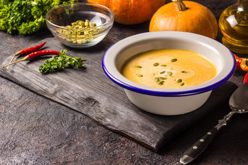 Seasonal autumn food - Spicy pumpkin soup with cream and pumpkin seeds.