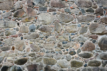 Stone wall of the old castle of granite rocks, old masonry. Texture, stonework.
