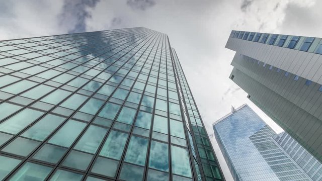 White clouds move fast over skyscraper building. Window reflection, time lapse video