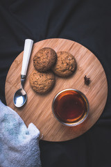 Cup of tea with oatmeal cookies and spoon on the wooden board top view