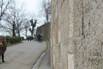 Fototapeta na wymiar Ancient stone defensive wall of the castle with unrecognized people at background in Budapest