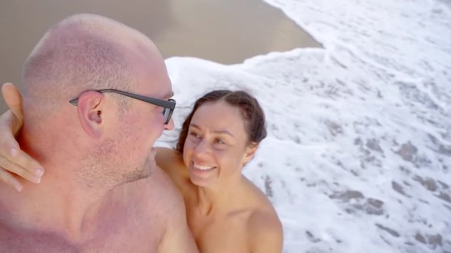 Happy couple french kissing on a beach shore on summer vacation.