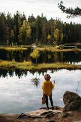 Fototapeta na wymiar Woman in a yellow poncho and hat in the autumn time in national park Nuuksio, Finland