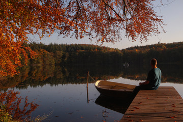 Fototapeta na wymiar einsamer Mann sitzt alleine am See im Herbst, Konzept Depression, burn-out, psychische Belastung, Symptome 