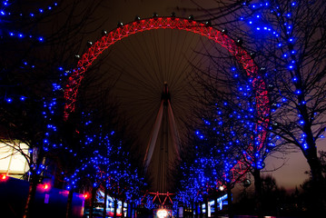 Ferris Wheel Illuminated in red with blue trees surrounding it