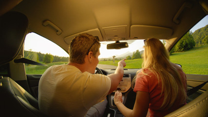 CLOSE UP: Young man pointing where the couple will drive during their road trip.