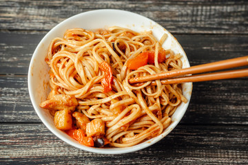WOK udon noodle with chicken and vegetables in a white plate on wooden background