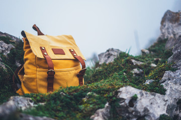Hipster hiker tourist yellow backpack closeup on background green grass nature in mountain, blurred panoramic landscape, traveler relax holiday concept, view planning wayroad in trip vacation © A_B_C