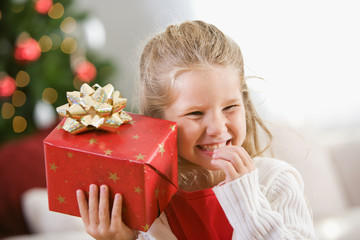 Christmas: Young Girl Holds Christmas Present To Ear
