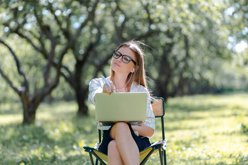 Business woman with a laptop in the Park sitting on a folding chair