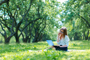 Business woman using laptop on lunch break in city park