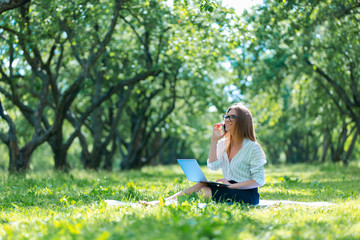 Naklejka na ściany i meble Business woman using laptop on lunch break in city park