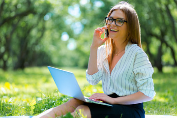Business woman using laptop on lunch break in city park
